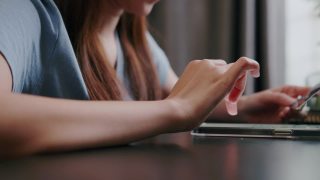 近距离的有吸引力的女人持有信用卡进行在线支付，而网上购物的智能手机视频素材模板下载