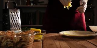 厨师双手戴着手套，把磨碎的奶酪扔在木桌上的玉米饼上