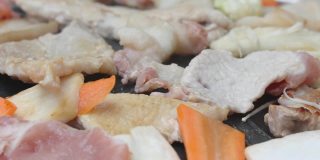 将牛肉、猪肉和杂菜放在热锅上烧烤。