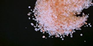粉红色喜马拉雅盐。喜马拉雅粉岩盐木勺黑色背景。粉喜马拉雅盐的细粒