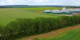 沼气发电厂。农业和温室综合设施。现代农场，绿色田野间有储罐。生物质能的生产。