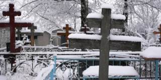 在冬天以慢动作拍摄的墓地上被雪覆盖的十字架的特写镜头