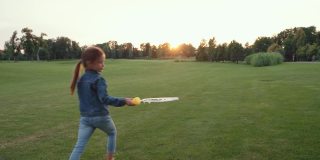无忧无虑的小女孩吹着肥皂泡，在夕阳下的绿色田野里独自玩耍