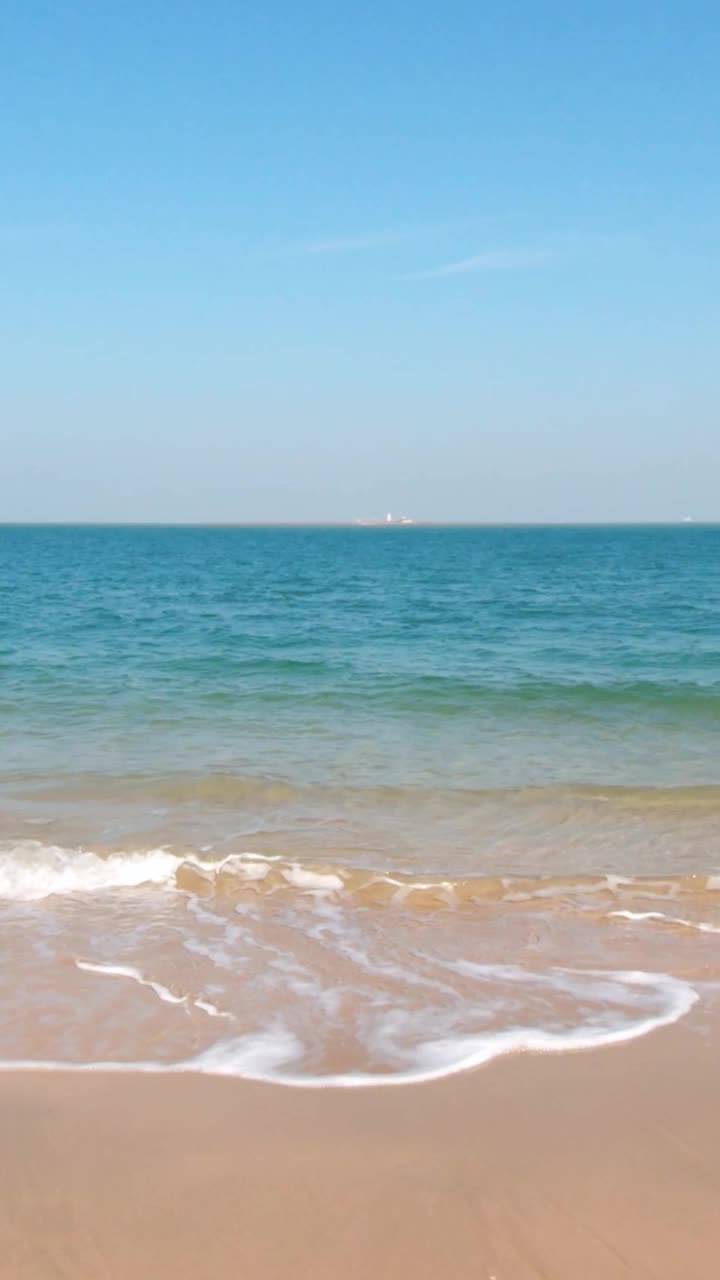 在印度古吉拉特邦Shivrajpur的蓝色旗帜海滩。海浪拍打着海滩的海岸。假期放松的概念。在海滩放松。夏天旅游的背景。