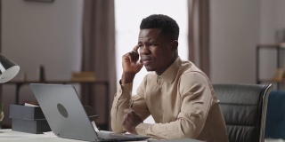 悲伤的美国黑人正在使用笔记本电脑在家办公，发现错误和错误的程序，愁眉苦脸，在家远程工作