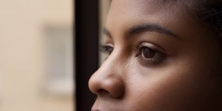 近距离的肖像，迷人的非洲裔美国妇女的眼睛看着窗外。