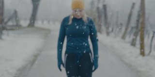 SLO MO Woman在雪地里慢跑穿过森林时停下来喘口气