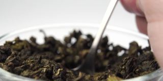 干的、卷好的绿茶叶子从茶匙中慢慢地堆成一堆