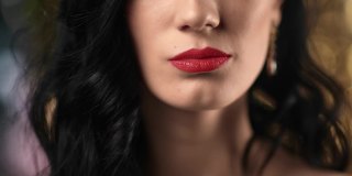 性感女性的嘴用红色的口红舔着嘴唇在夜总会摆出亮焦的姿势。近距离拍摄4k红色相机