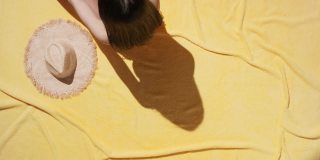 穿着泳衣的女人躺在毛巾布毯子上晒太阳
