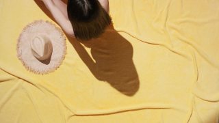 穿着泳衣的女人躺在毛巾布毯子上晒太阳视频素材模板下载
