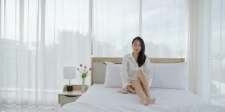 美丽的亚洲女人在她的床上伸展自己的早晨。