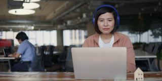 亚洲商务女性戴着耳机坐在共同工作空间的商务咨询会议。营销策划。在网络空间里用免费的Wi-Fi工作。无线技术概念