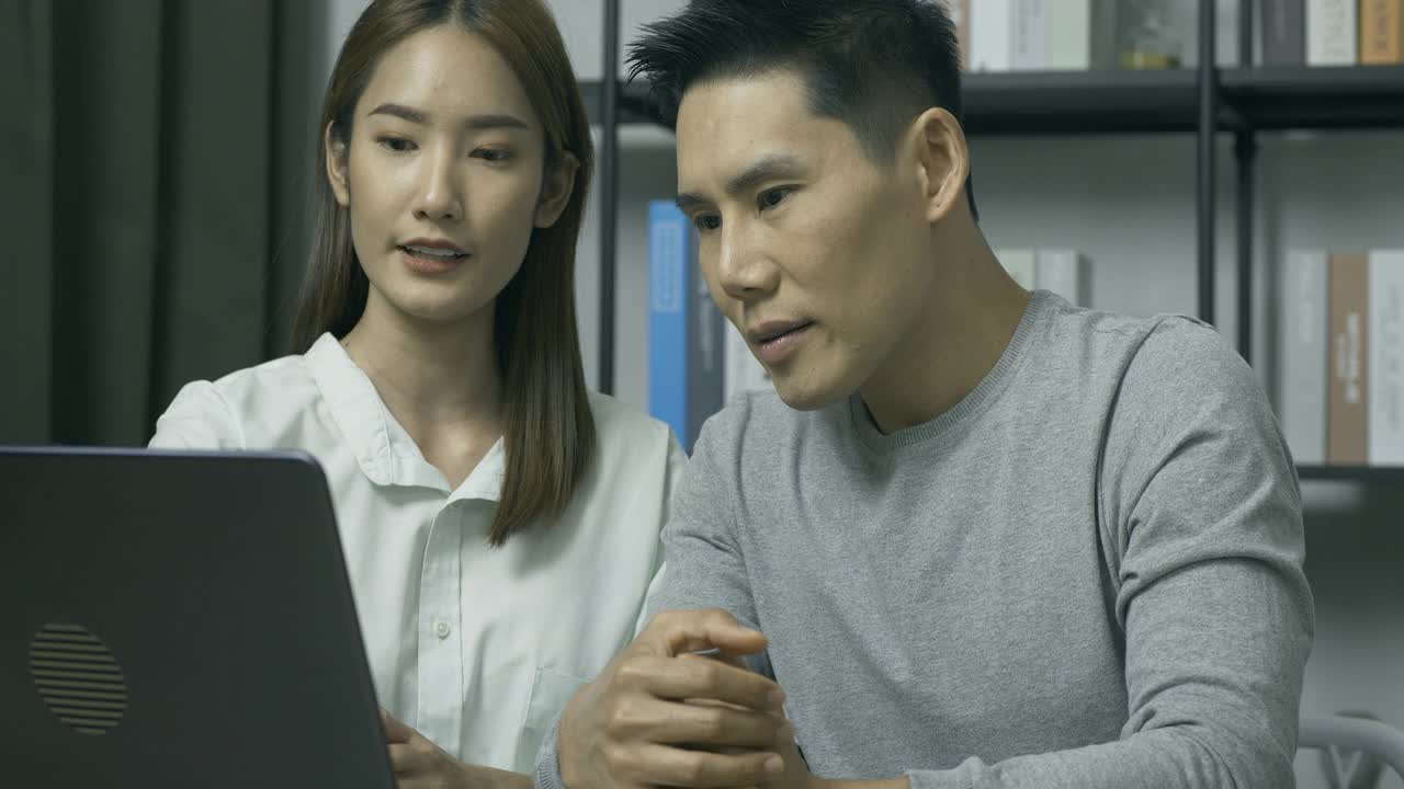 专注于年轻亚洲女性使用笔记本电脑，咨询和展示她的报告给同事在工作场所。