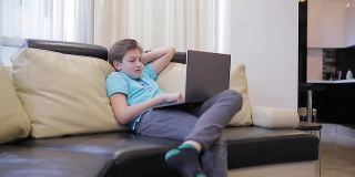 小男孩在隔离期间在家看有趣的电影。青少年坐在家里舒适的沙发上，孩子和小玩意概念。