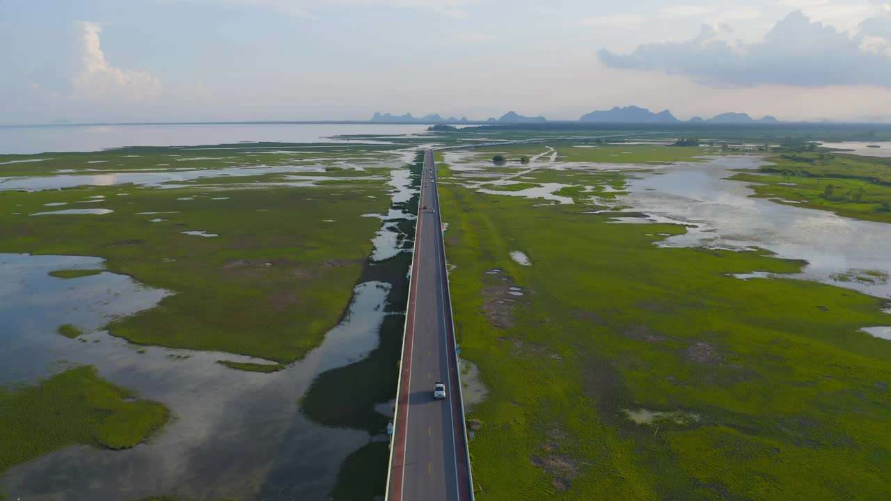 鸟瞰图街道公路公路与沼泽或泻湖在攀牙湾，湖，海或河流在国家公园和山或小山在泰国。自然景观背景。