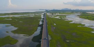 鸟瞰图街道公路公路与沼泽或泻湖在攀牙湾，湖，海或河流在国家公园和山或小山在泰国。自然景观背景。