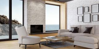 白色斯堪的纳维亚客厅与生态壁炉。现代室内概念。夏天的海边的概念。
