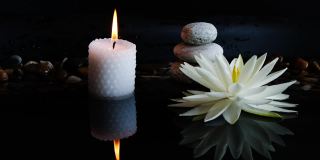 Spa的背景是白色的莲花，睡莲花，平衡的石头和燃烧的蜡烛