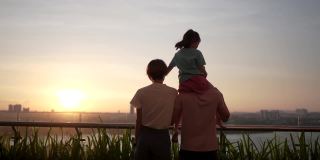 一个亚洲华人家庭和一个孩子在户外欣赏春天的日落美景。