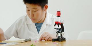 亚洲小学生穿着实验服一起在科学课上使用显微镜，教育理念。