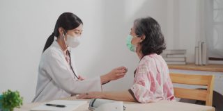 亚洲女医生伸展年长女性病人的手臂对家庭护理员