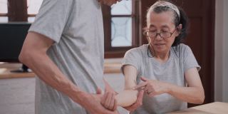 老年女性与成年男性在家做手臂理疗
