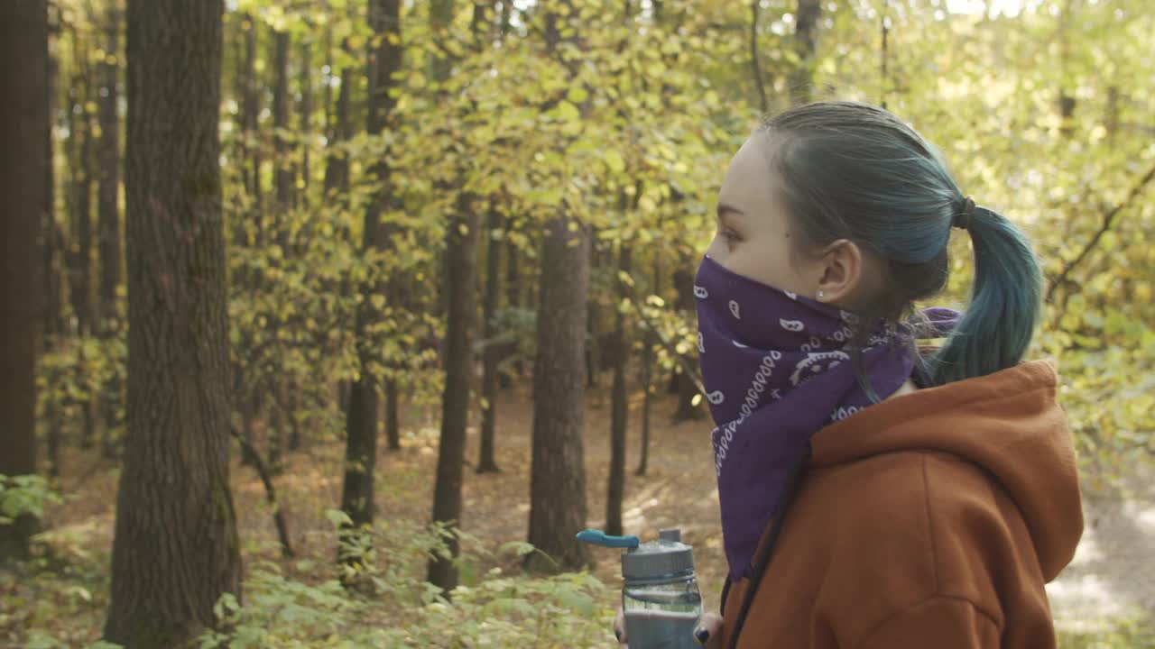 十几岁的女孩戴着替代面部头巾，在运动或跑步后在公园休息和喝水