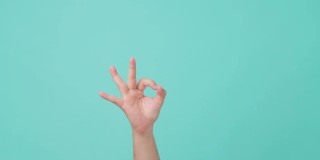 人的手举起的特写，手势ok手势或戒指手势，拇指和食指围成一个圈，并保持其他手指伸直。在孤立的蓝屏背景中看到。
