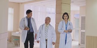 一组由医生、护士和助理组成的亚洲团队走过医院的走廊。有专业医疗经验的医生在室内行走，为拯救生命而工作。缓慢的运动。