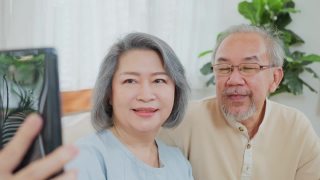 亚洲老年夫妇的特写，老年妇女和老年男子使用手机视频通话与儿子，女儿和在家里与孙辈交谈。祖父母对通过互联网交流感到高兴视频素材模板下载