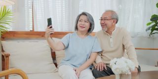 亚洲美丽的老女人和老男人夫妇在家里用手机和儿子、女儿视频通话，和孙子孙女聊天。祖父母对通过互联网交流感到高兴