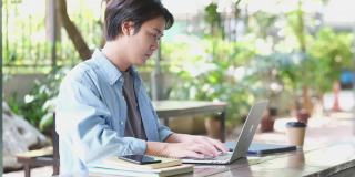 年轻的亚洲男子伸展放松从工作的笔记本电脑在校园，在家里工作