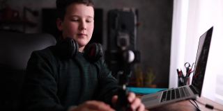 十岁的玩家，调整三脚架和手机，在他的频道直播之前，直播他的在线视频游戏比赛