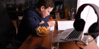 COVID-19大流行期间，专心在家上学的男孩在他舒适的家里做作业