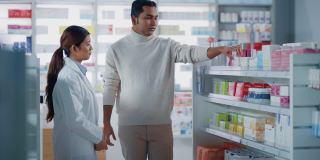 药店:女性亚洲药剂师帮助印度男性客户与推荐，并建议购买药物，药物，维生素。现代药店货架与保健产品