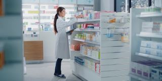 药店:美丽的亚洲药剂师使用数字平板电脑，检查库存的药物，药物，维生素，保健产品的货架上。药店专业药剂师