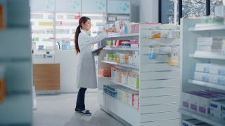 药店:美丽的亚洲药剂师使用数字平板电脑，检查库存的药物，药物，维生素，保健产品的货架上。药店专业药剂师视频素材模板下载