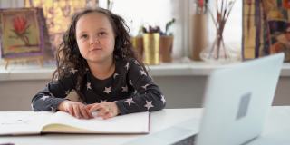 在家上学的概念:带着耳机和笔记本电脑的小女孩