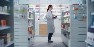 药店:美丽的中国药剂师使用数字平板电脑，检查库存的药品，药物，维生素，保健产品的货架上。药店专业药剂师