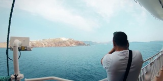 摄影师在从阿西诺斯港出发的船上拍摄圣托里尼岛
