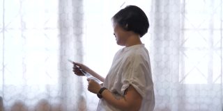 一名亚洲孕妇在家里的床上抱着并看着她婴儿的超声波扫描