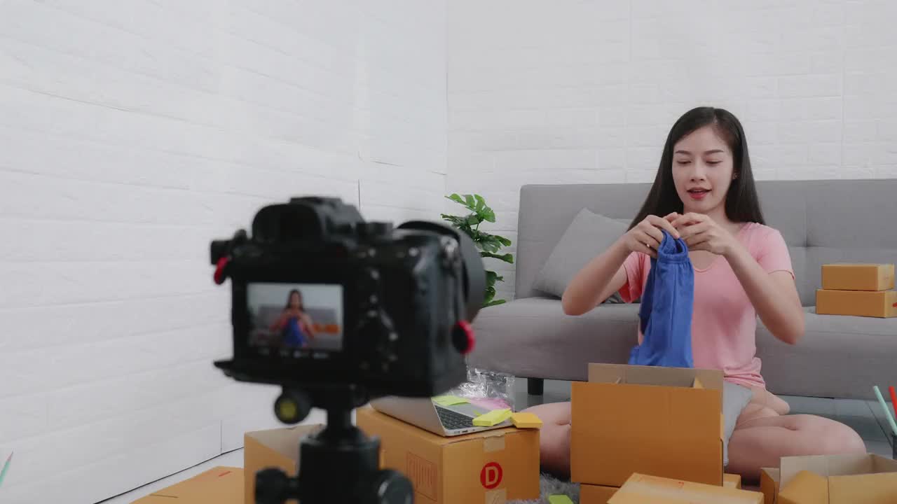 亚洲女性小企业主利用现场摄像机在网上卖衣服