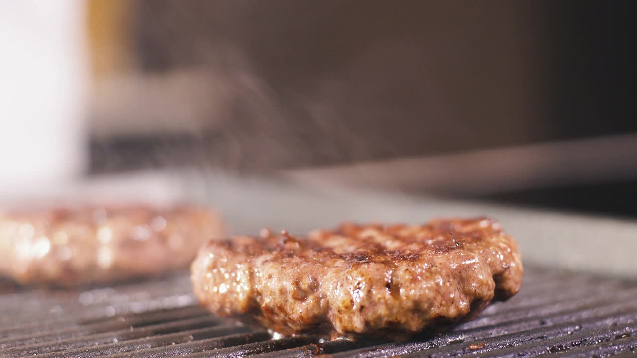 男人把芝士放在肉上，汉堡肉排放在热烤盘上。在专业餐厅厨房烹饪食物。准备晚餐的人。制作美味的汉堡。美味的家现代美食近