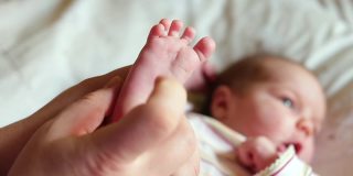 演示婴儿脚反射。妈妈按脚趾脚，手指握紧松开。