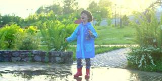 快乐可爱的小男孩，孩子，跑，玩，玩跳过水坑在雨衣和胶靴。笑着笑着的男孩在公园里，雨雪春夏秋坏天气水坑冷