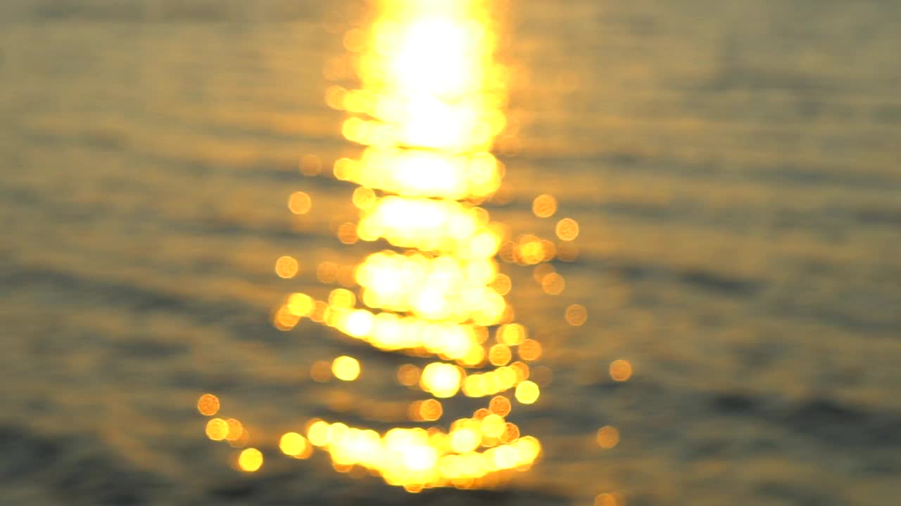 夕阳西下的海边，海边的沙滩。一个男人的手在阳光下的背景海水的性质。眩目的夕阳透过手指，旅游旅游旅行者快乐的假期夏季邮轮梦想