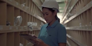 起重机跟随录像拍摄的亚洲女工人巡逻货物放在货架上的仓库