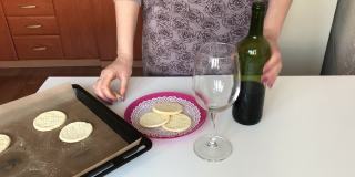 一位妇女将干红葡萄酒倒进玻璃杯。旁边一盘未发酵的玉米粉上。