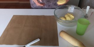 一个妇女用玉米面做无酵面包。将面团分成小块，撒上面粉，放在不粘的垫子上。